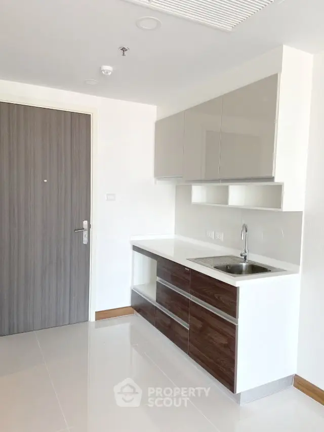 Modern minimalist kitchen with sleek cabinetry and compact design in a bright apartment.