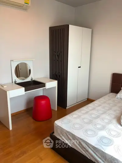 Modern bedroom with stylish furniture and wooden flooring, featuring a sleek wardrobe and vanity desk.