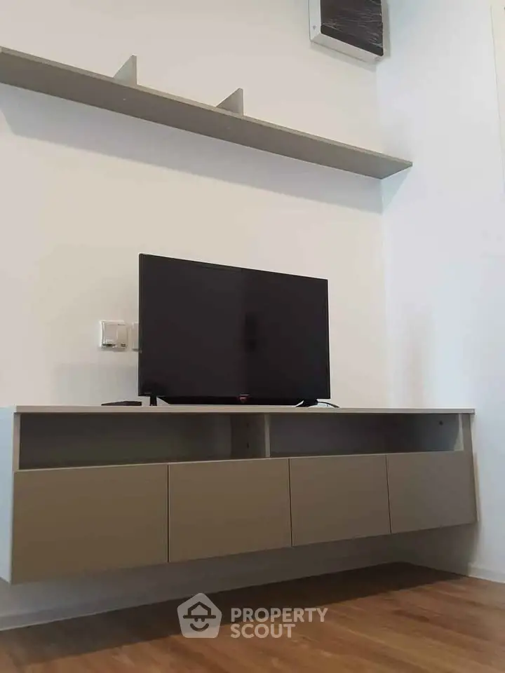 Modern living room with sleek TV cabinet and wall-mounted shelf.