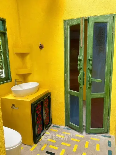 Vibrant yellow bathroom with green accents and modern sink design