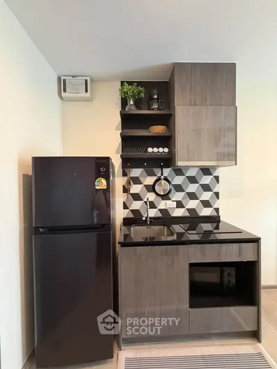 Modern compact kitchen with sleek black appliances and stylish geometric backsplash.