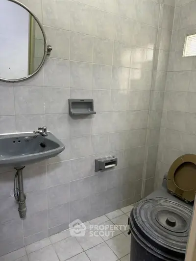 Compact bathroom with gray tiles and basic fixtures, ideal for small spaces.
