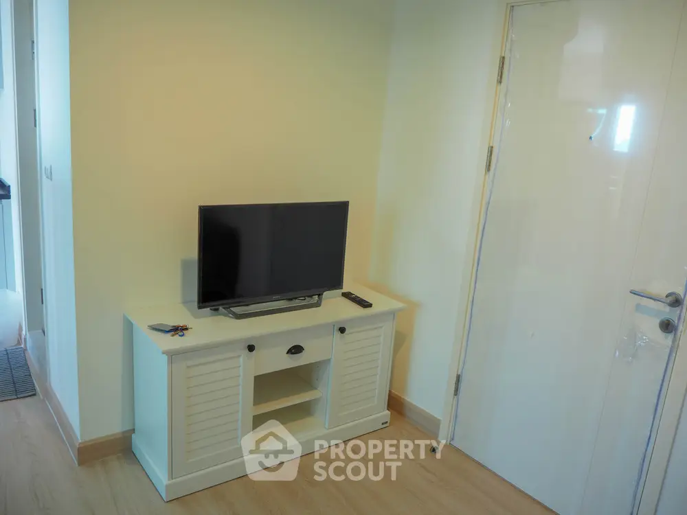 Modern living room with sleek TV stand and flat-screen TV, showcasing minimalist design and bright ambiance.