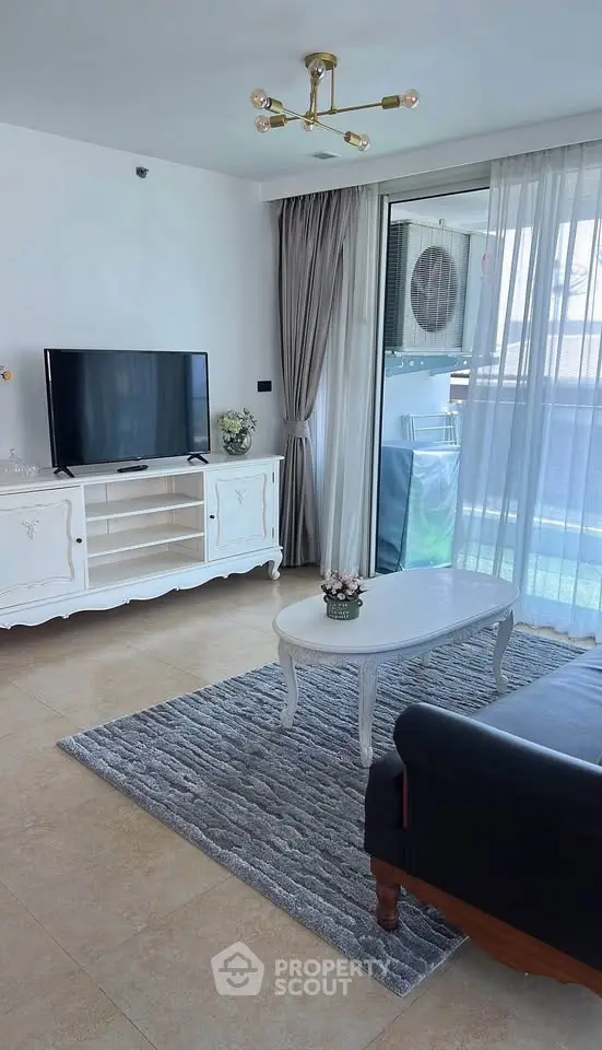 Elegant living room with modern decor and balcony view, featuring a stylish TV stand and cozy seating area.