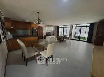 Spacious open-layout living and dining area with modern kitchen and large windows.