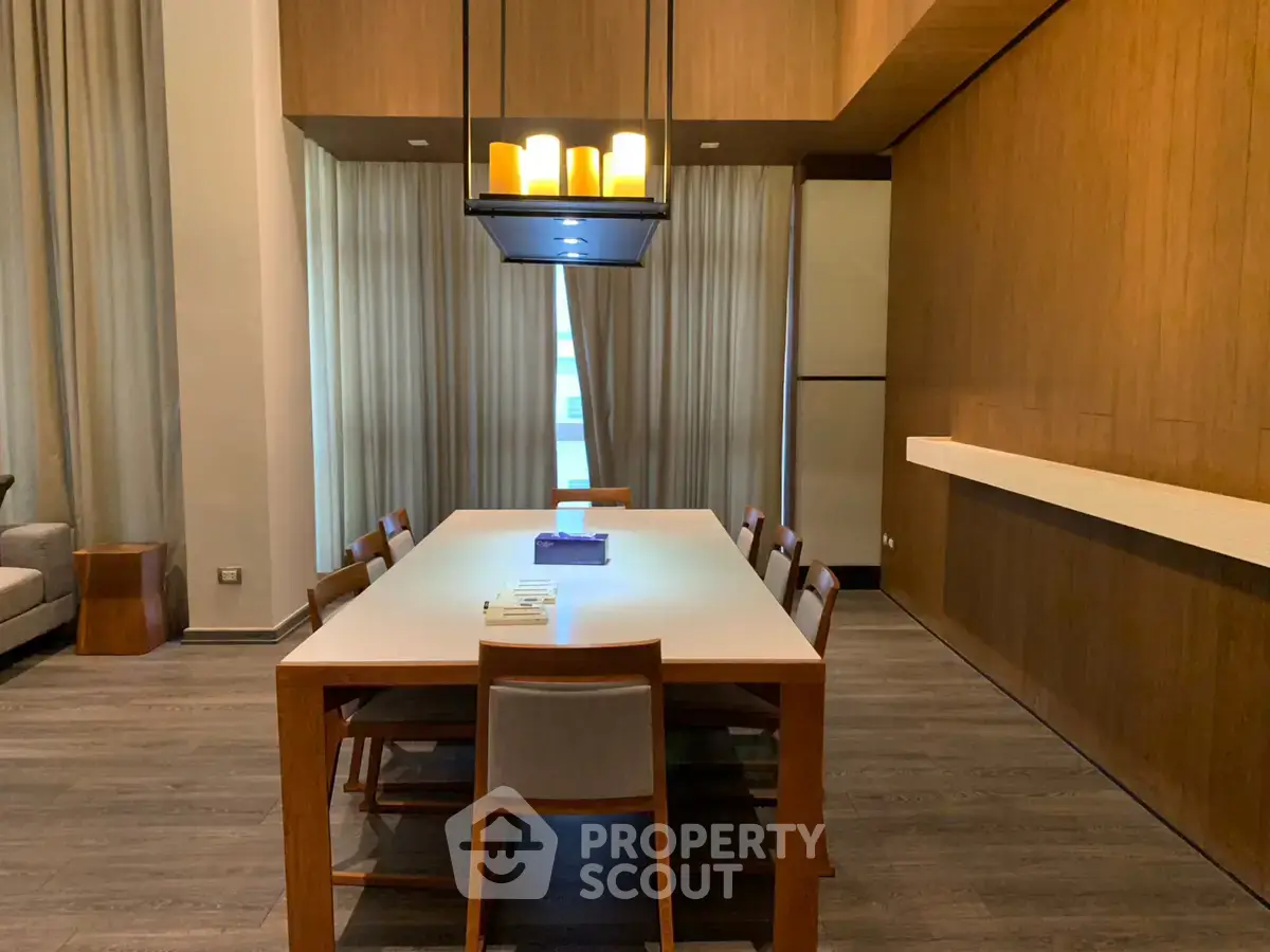 Elegant dining area with modern lighting and wooden accents in a spacious apartment.