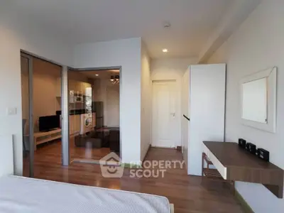Modern bedroom with wooden flooring and sliding glass doors leading to a cozy living area.