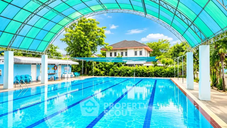 Stunning outdoor pool with a modern canopy in a lush residential setting.