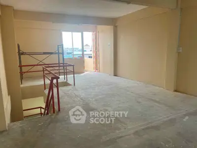 Spacious unfinished interior with large window and staircase, ideal for customization.