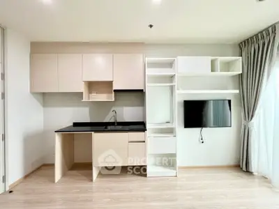 Modern studio apartment with sleek kitchen featuring built-in appliances and ample storage, complemented by light wood flooring and neutral tones.