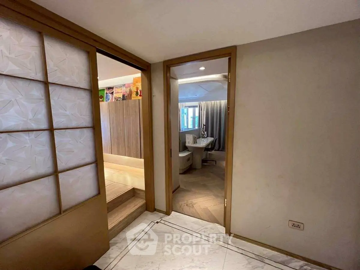 Modern interior hallway leading to a stylish bathroom with wooden accents and elegant design.