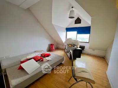 Cozy attic bedroom with sloped ceiling and large window view