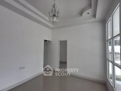 Spacious empty room with elegant chandelier and large windows