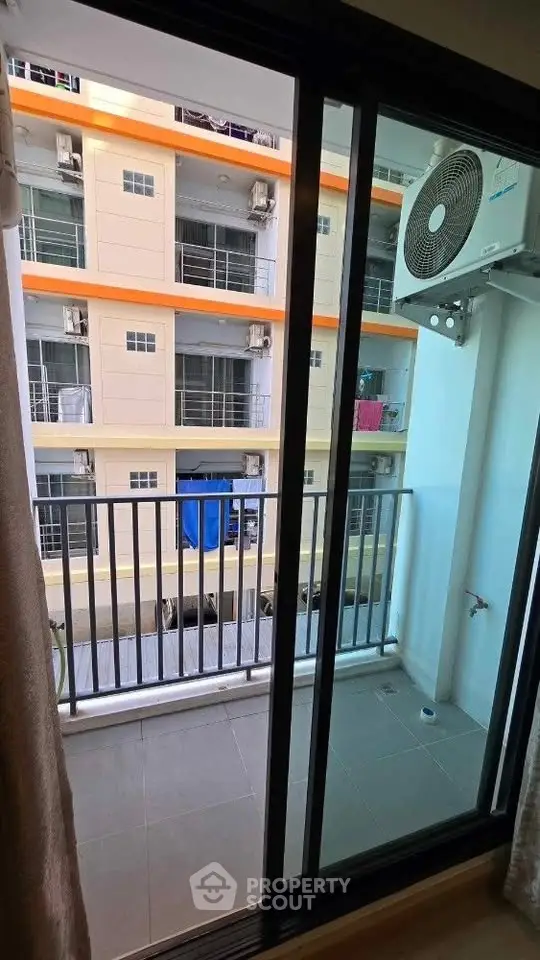 Compact balcony view with air conditioning unit in modern apartment complex.