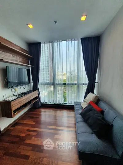 Modern living room with large window and city view, featuring sleek wooden flooring and contemporary furniture.