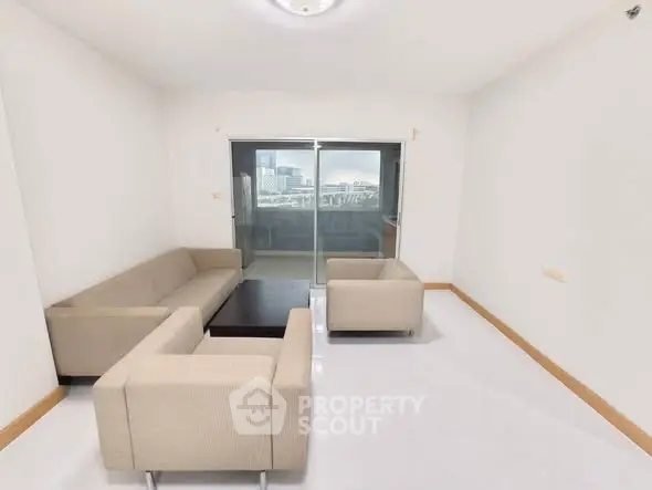 Spacious living room with modern furniture and balcony view in urban apartment.