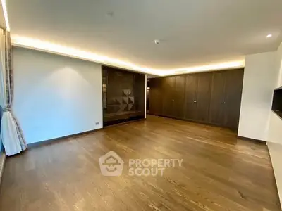 Spacious empty living room with wooden flooring and modern lighting