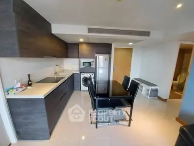 Modern kitchen with sleek cabinetry and dining area in open layout apartment.