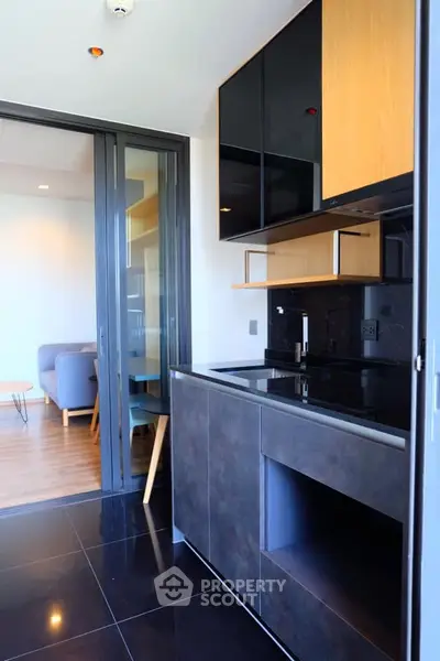 Modern kitchen with sleek cabinetry and open layout leading to a stylish living area.