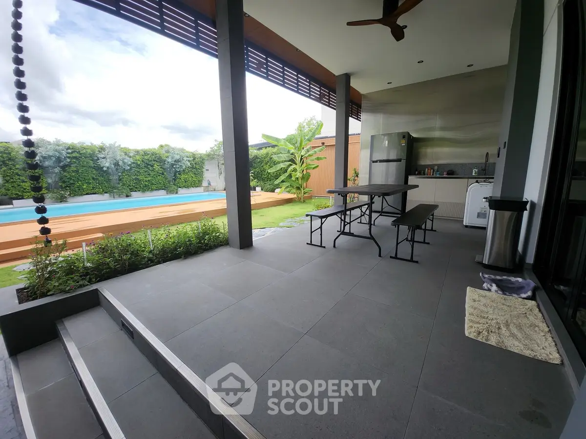 Modern outdoor patio with pool and garden view, featuring sleek design and spacious layout.