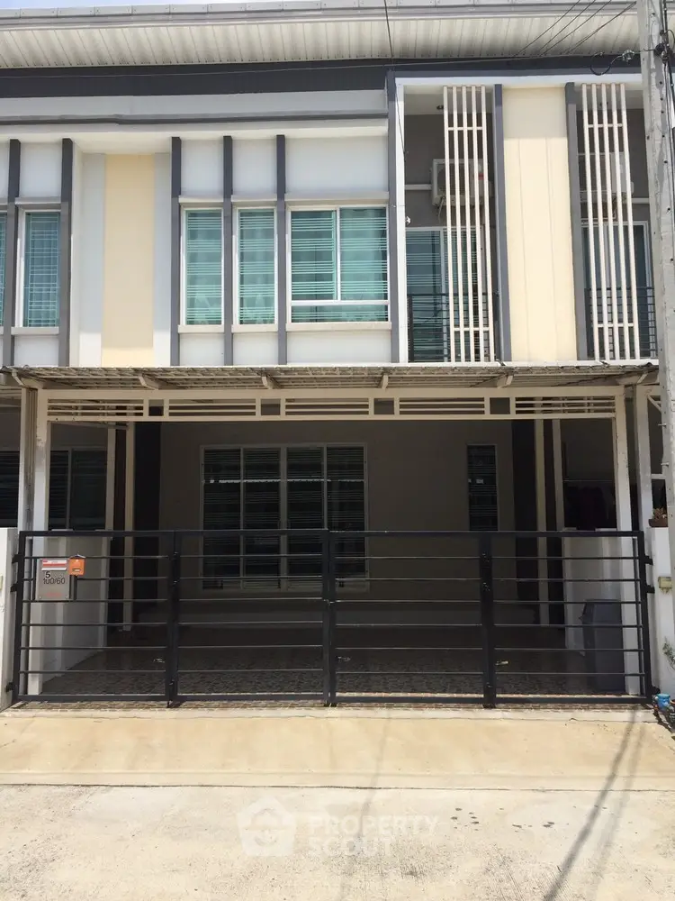 Modern townhouse exterior with gated parking and sleek architectural design.