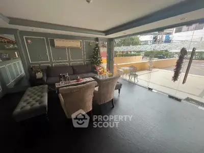 Stylish living room with modern decor and large glass windows offering street view.