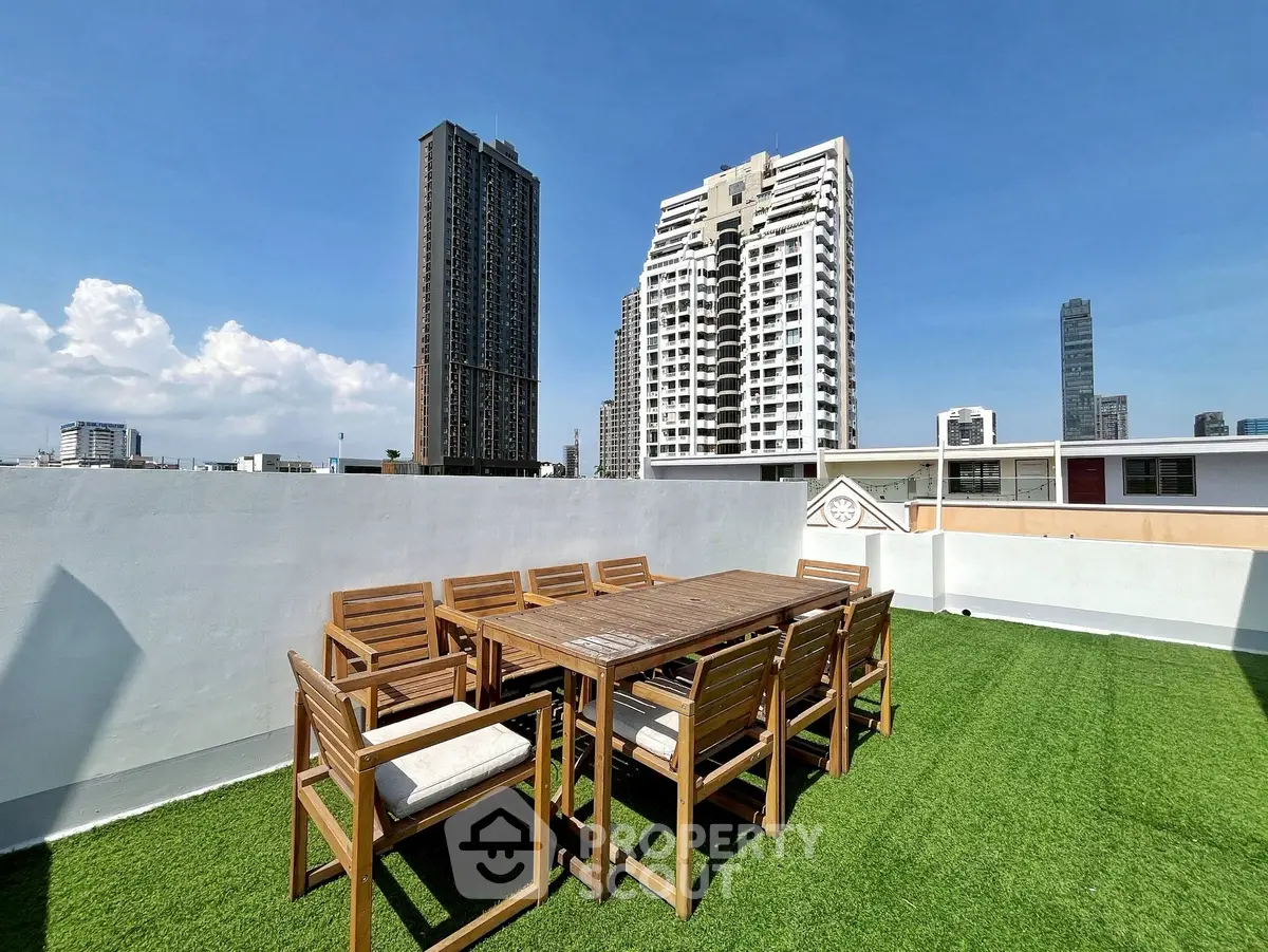 Stunning rooftop terrace with city skyline views and outdoor dining set on artificial grass.