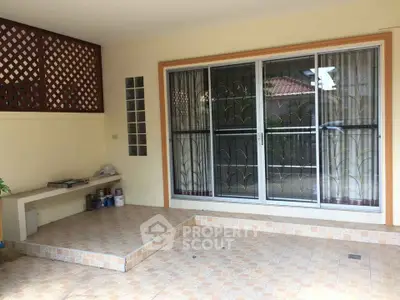 Charming patio with tiled flooring and sliding glass doors in a cozy residential setting.