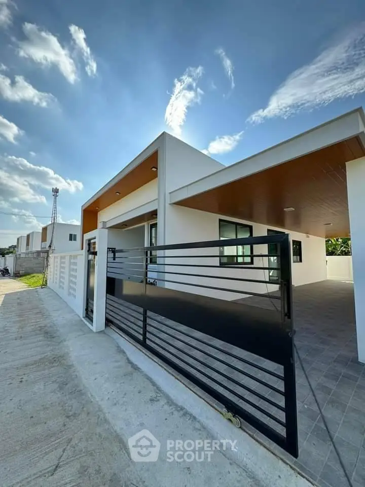 Modern single-story house with sleek design and spacious driveway under clear blue sky.