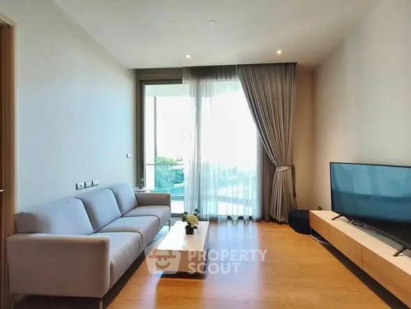 Modern living room with sleek furniture and large window offering natural light.
