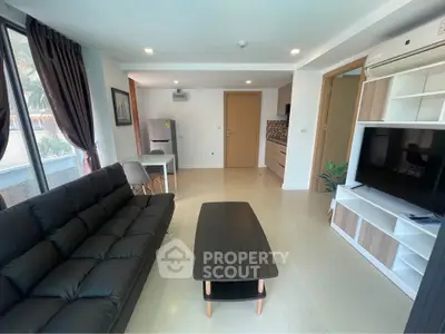 Modern living room with sleek black sofa and stylish entertainment center.