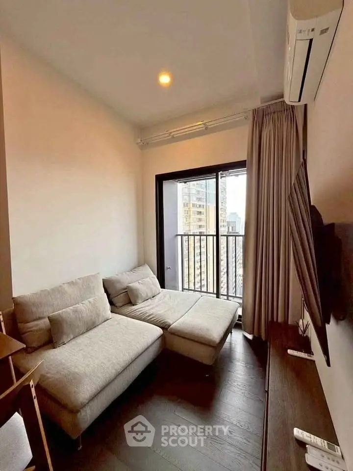 Cozy living room with modern sofa and city view balcony in high-rise apartment.