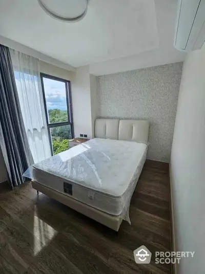 Bright bedroom with large window and modern decor, featuring a comfortable bed and scenic view.