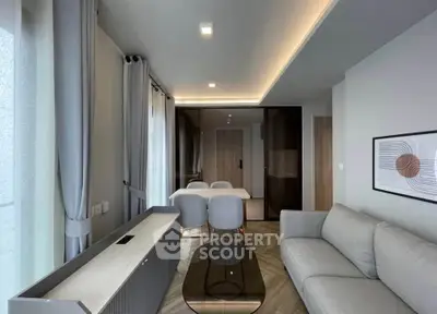 Modern living room with elegant decor and open dining area, featuring sleek furniture and ambient lighting.
