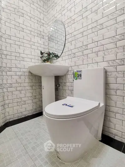 Modern bathroom with sleek white toilet and stylish sink against brick-patterned tiles.