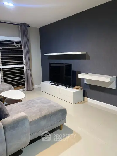 Modern living room with sleek furniture and wall-mounted TV in a stylish apartment.