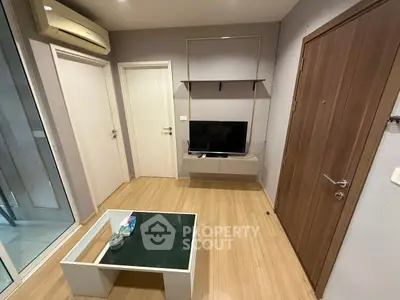 Modern living room with TV, glass coffee table, and air conditioning unit