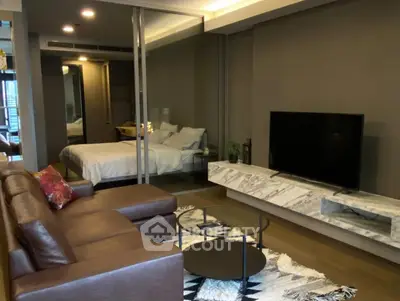 Modern living room with sleek furniture and a view into a cozy bedroom