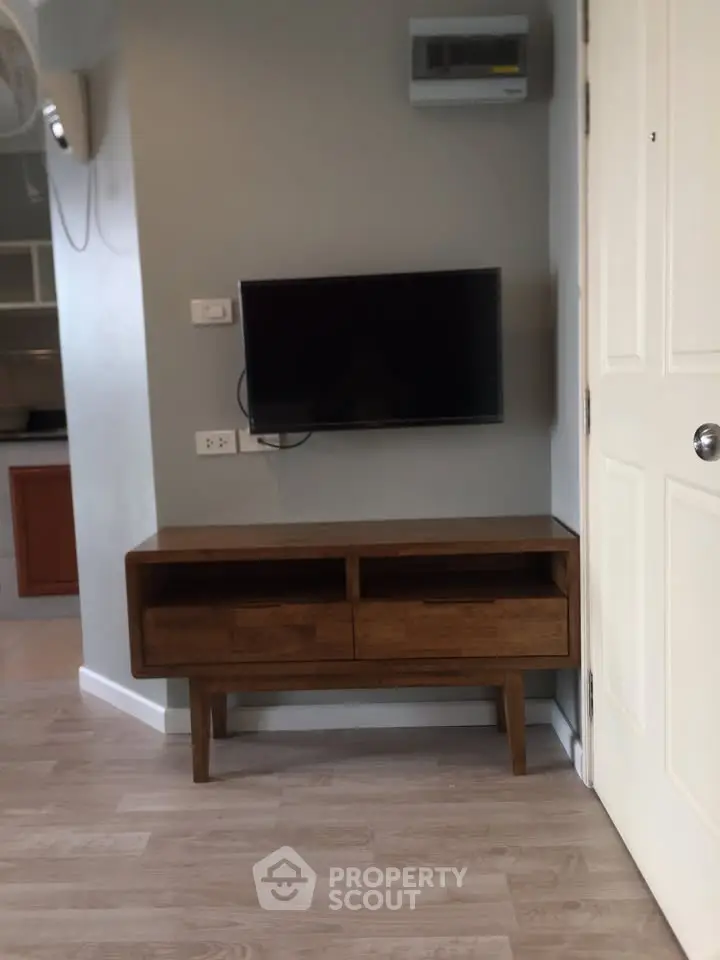 Modern living room corner with wall-mounted TV and wooden console table.