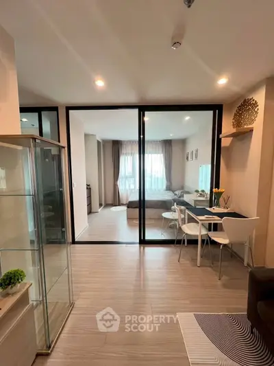 Modern open-plan living room with dining area and glass partition, featuring stylish decor.