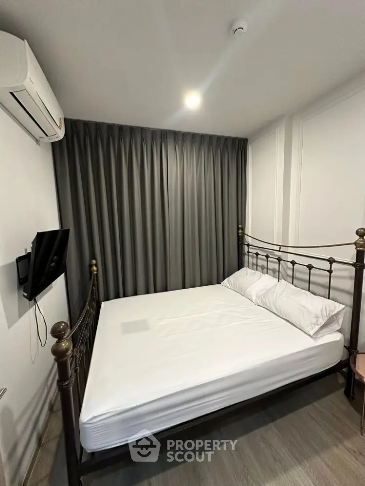 Cozy bedroom with elegant metal bed frame and wall-mounted TV, perfect for modern living.