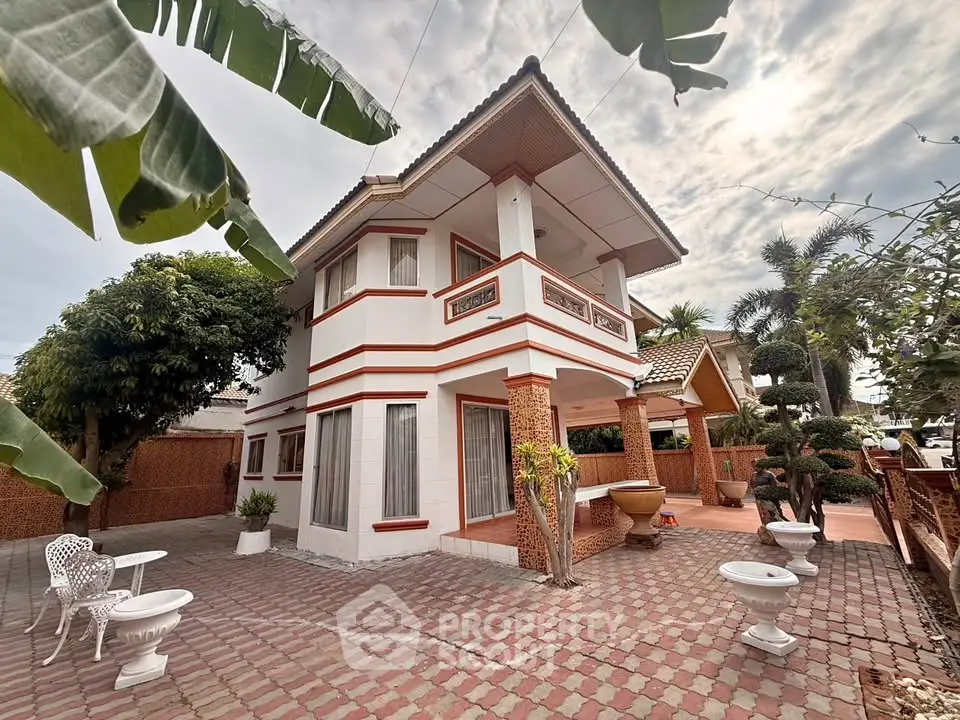 Charming two-story house with spacious patio and lush garden, perfect for family living.