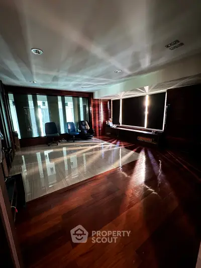 Spacious living room with wooden flooring and large windows, perfect for natural light and modern living.