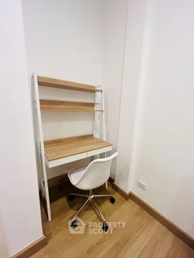 Modern minimalist study nook with wooden desk and white chair in cozy corner.
