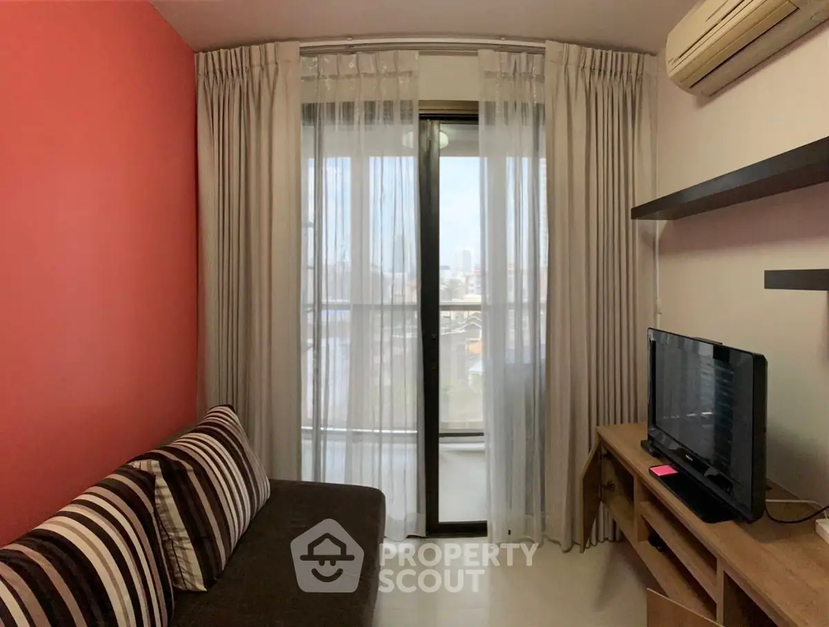 Cozy living room with balcony view, striped sofa, and modern TV setup.