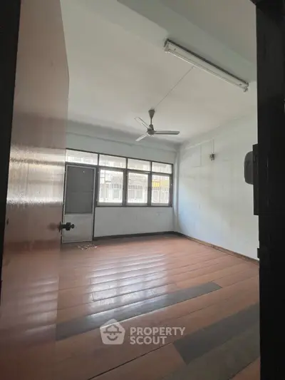Spacious empty room with wooden flooring and large windows, ideal for customization.