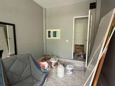 Cozy room under renovation with modern gray walls and tiled floor, featuring a small window and open door.