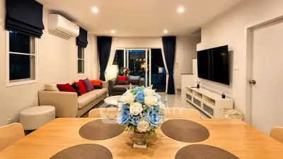 Spacious modern living room with elegant decor and large TV, perfect for relaxation and entertainment.