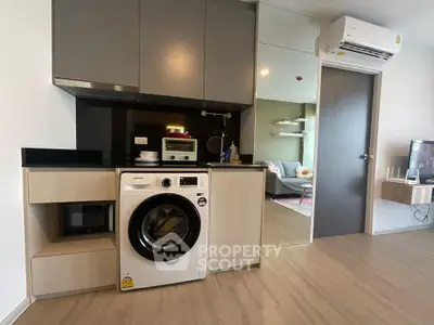 Modern apartment interior with sleek kitchen and washing machine, featuring open layout and stylish decor.