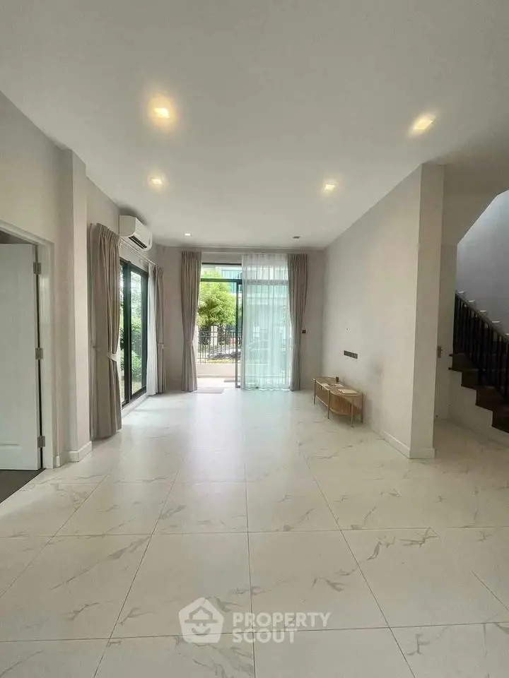 Spacious modern living room with large windows and elegant tile flooring